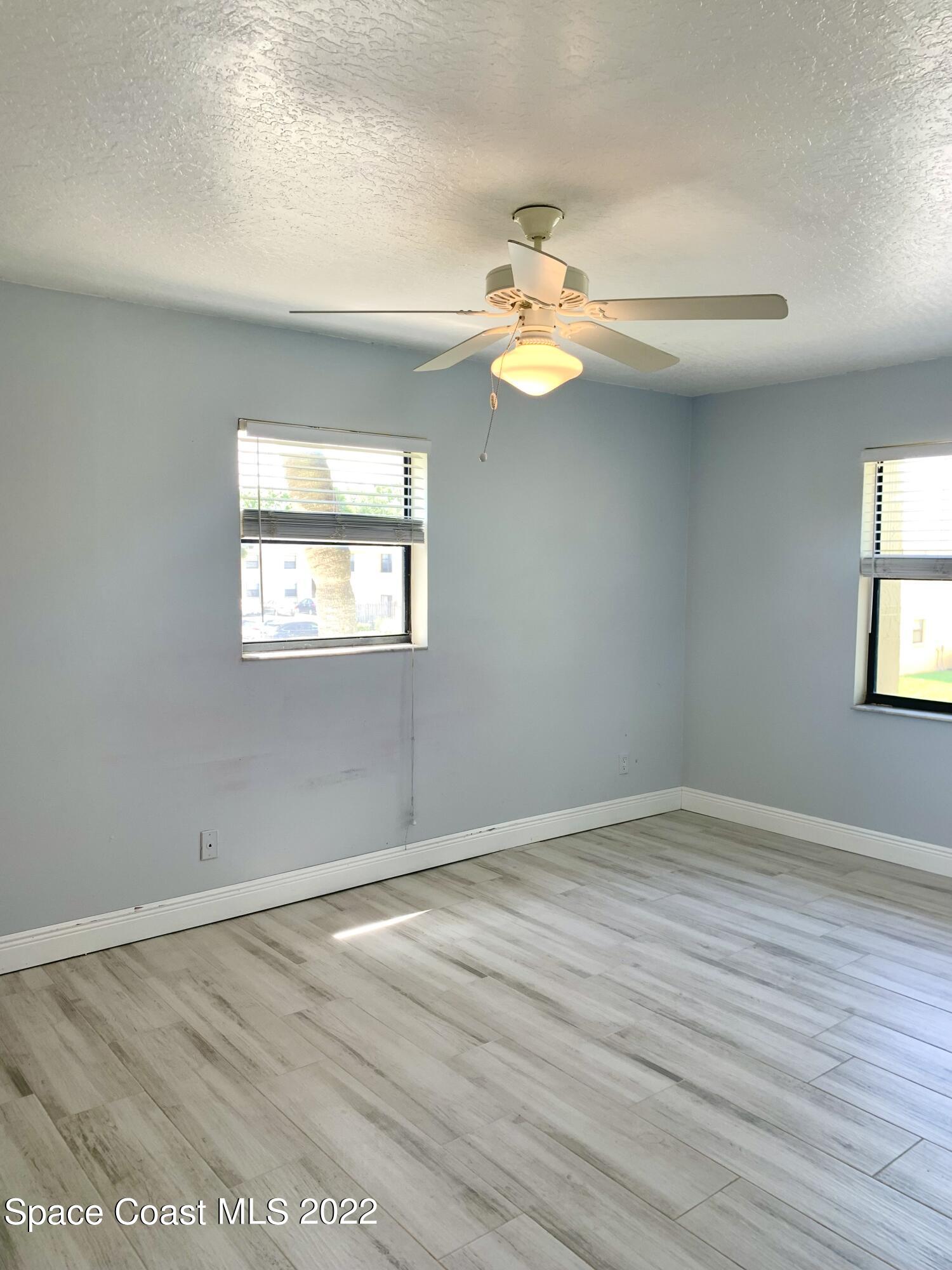 584 North Wickham Road, Unit 82 Melbourne, FL 32935 - Photo 9 of 43 an empty room with wooden floor and windows