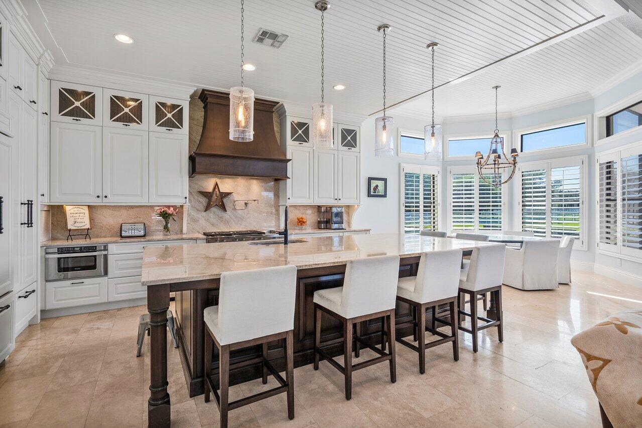 9891 Equus Circle Boynton Beach, FL 33472 - Photo 22 of 88 a kitchen with kitchen island a dining table chairs and white cabinets