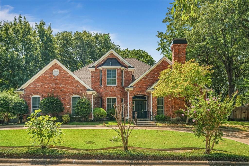 Traditional-style house with a front lawn, a chimney, and brick siding