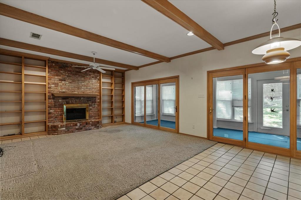 9 Willow Ridge Road Greenville, TX 75402 - Photo 11 of 31 Unfurnished living room with light tile patterned floors, light carpet, a brick fireplace, beamed ceiling, and built in features