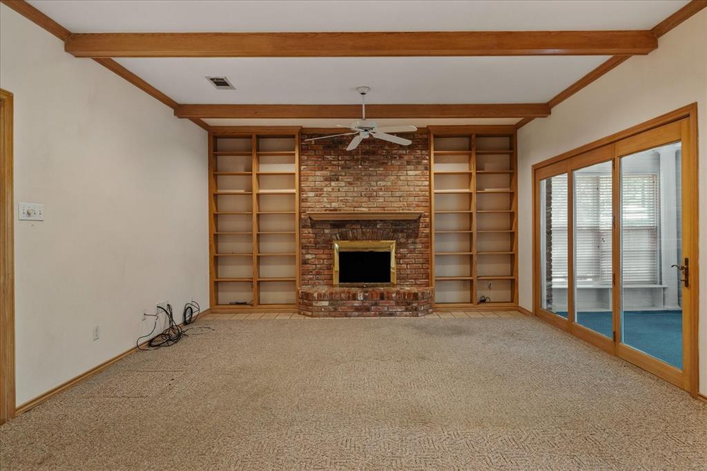 9 Willow Ridge Road Greenville, TX 75402 - Photo 12 of 31 Unfurnished living room featuring a fireplace, carpet flooring, beamed ceiling, built in features, and a ceiling fan