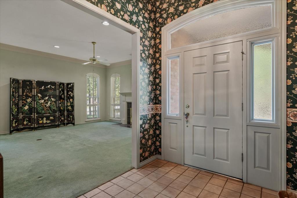 9 Willow Ridge Road Greenville, TX 75402 - Photo 4 of 31 Tiled entrance foyer featuring wallpapered walls, crown molding, carpet floors, a fireplace with flush hearth, and ceiling fan