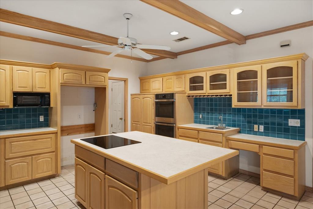 9 Willow Ridge Road Greenville, TX 75402 - Photo 10 of 31 Kitchen featuring decorative backsplash, glass insert cabinets, light countertops, a kitchen island, and beam ceiling
