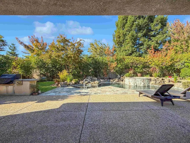 a view of a patio with table and chairs and floor to ceiling window and potted plants