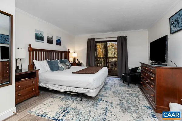 a bedroom with a bed and a flat tv screen on dresser