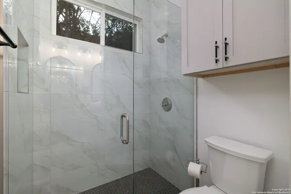 a bedroom with a bed a mirror on the wall and a window