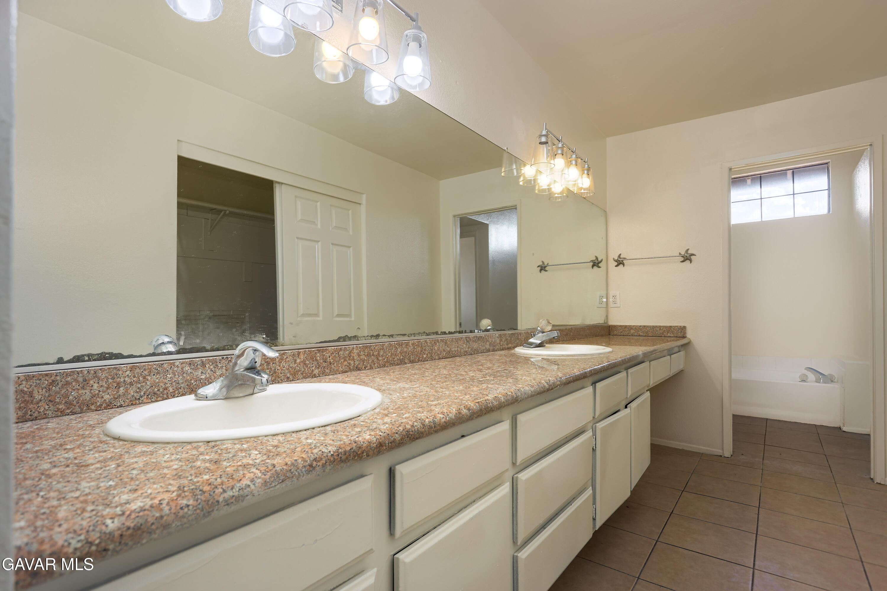 5217 East Ave R 4 Palmdale, CA 93552 - Photo 21 of 33 a bathroom with a granite countertop sink a large mirror and a shower