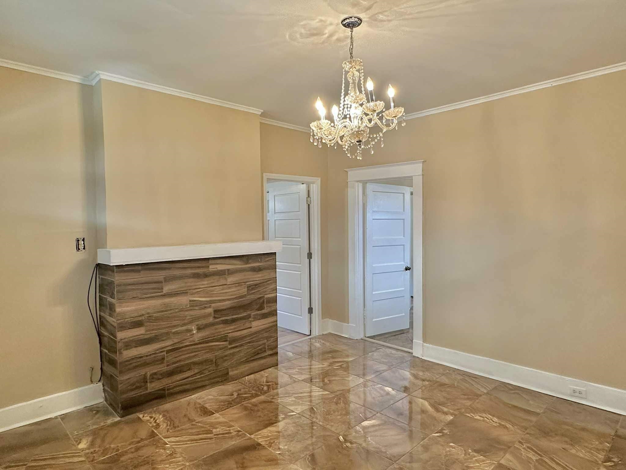 896 Orphanage Avenue Memphis, TN 38107 - Photo 5 of 17 Unfurnished dining area with marble finish flooring, crown molding, and a chandelier