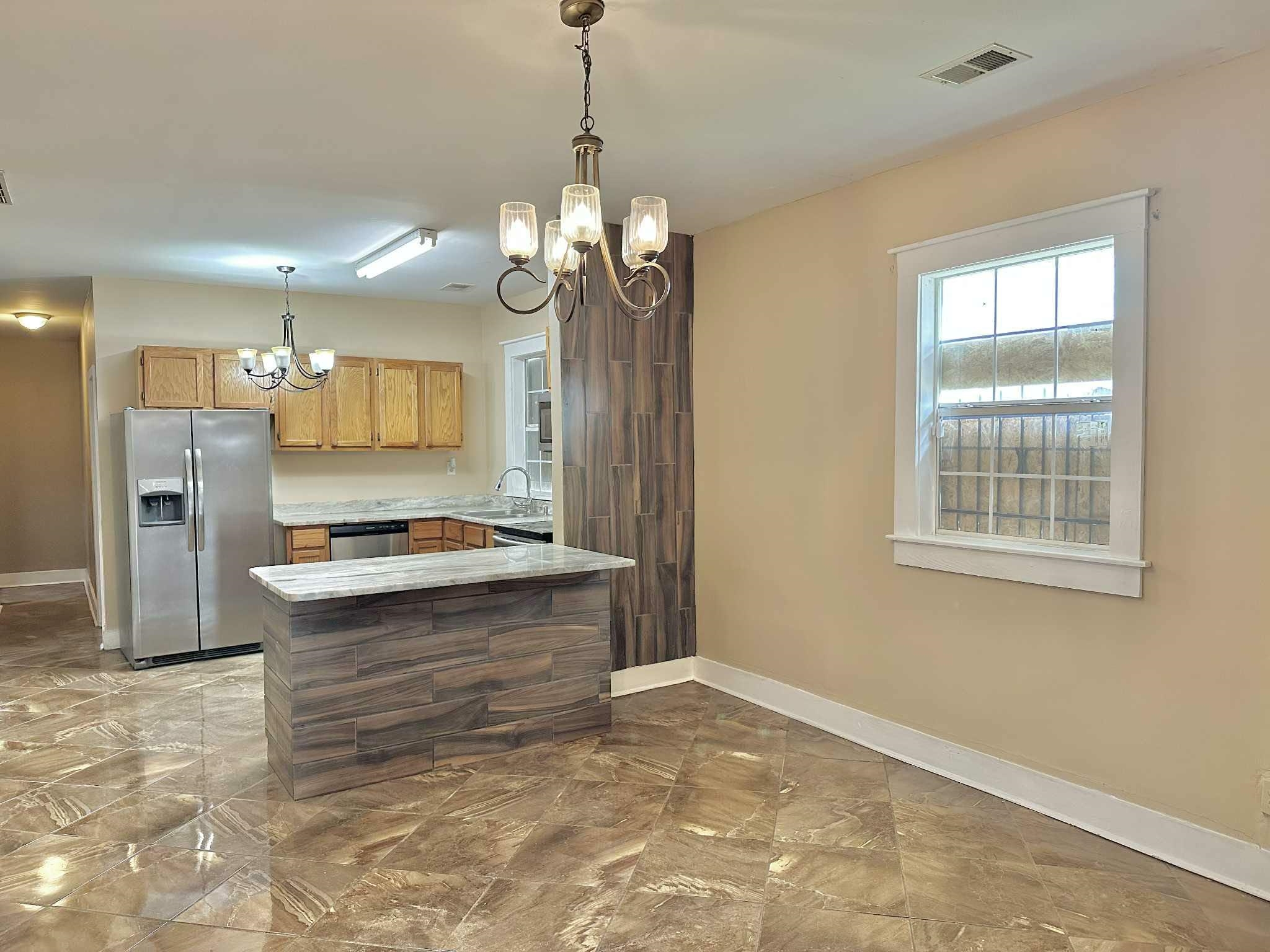 896 Orphanage Avenue Memphis, TN 38107 - Photo 6 of 17 Kitchen featuring a chandelier, appliances with stainless steel finishes, hanging light fixtures, a peninsula, and light marble finish floors