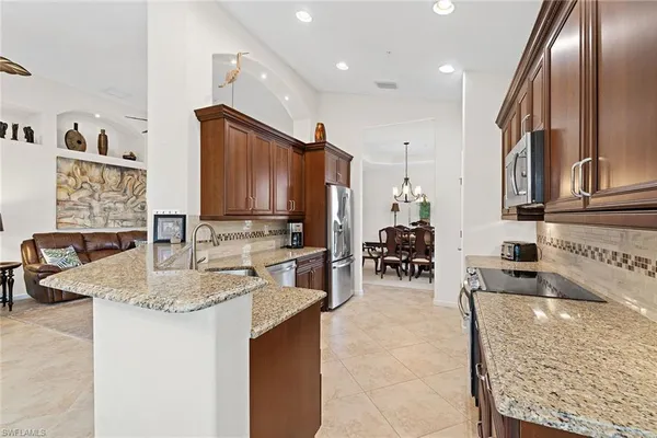 a kitchen with stainless steel appliances kitchen island granite countertop a refrigerator and a stove top oven