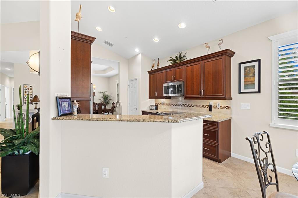 6669 Alden Woods Circle, Unit 7201 Naples, FL 34113 - Photo 14 of 28 a kitchen with stainless steel appliances kitchen island granite countertop a refrigerator and a stove top oven