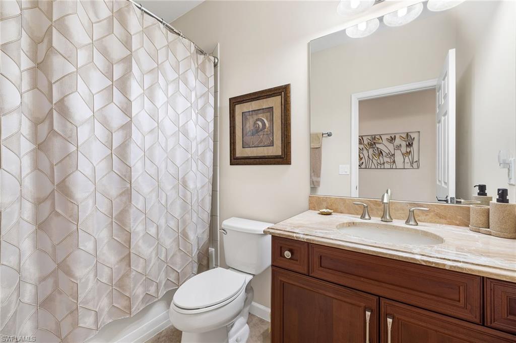 6669 Alden Woods Circle, Unit 7201 Naples, FL 34113 - Photo 21 of 28 a bathroom with a granite countertop sink mirror vanity and toilet