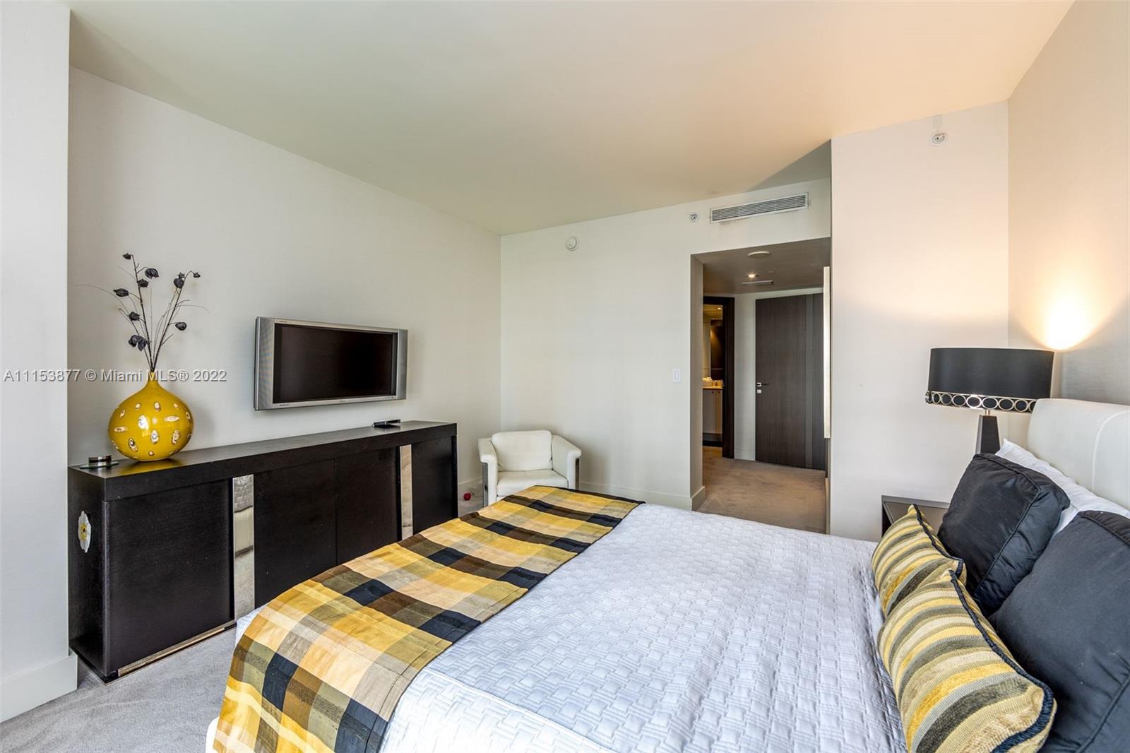 901 Brickell Key Boulevard, Unit 704 Miami, FL 33131 - Photo 14 of 39 a bedroom with a bed and a flat tv screen on dresser