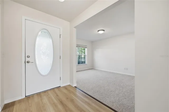 a view of a hallway to a room with wooden floor and a cabinet
