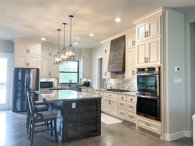 a kitchen with stainless steel appliances granite countertop a stove refrigerator and cabinets