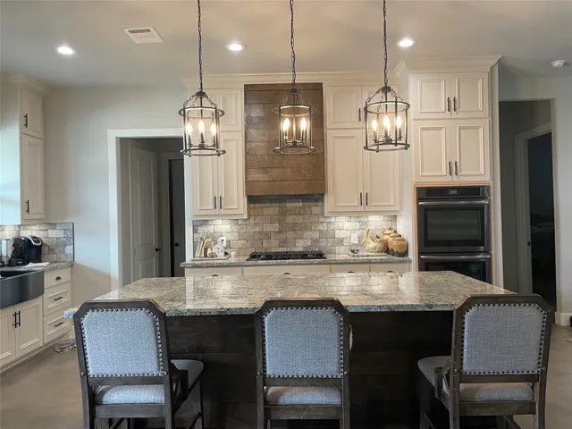 a kitchen with granite countertop a table chairs stove and refrigerator