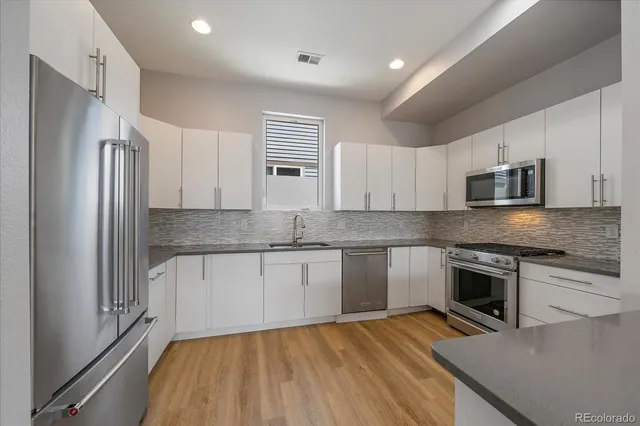 a kitchen with stainless steel appliances granite countertop a refrigerator a stove top oven a sink and dishwasher