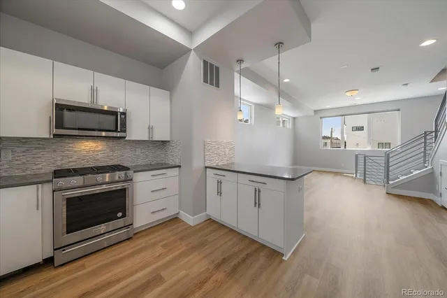 a kitchen with stainless steel appliances granite countertop a stove a sink and a microwave