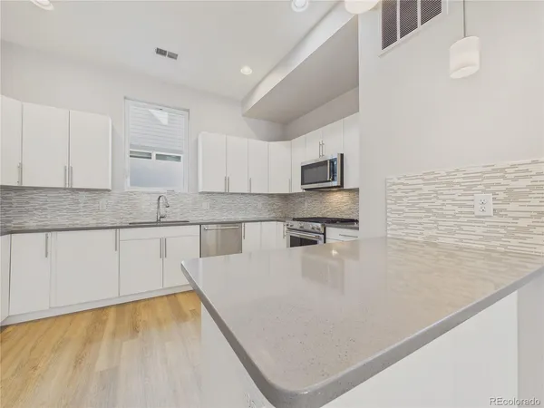 a kitchen with stainless steel appliances granite countertop a sink a stove top oven a counter space and cabinets