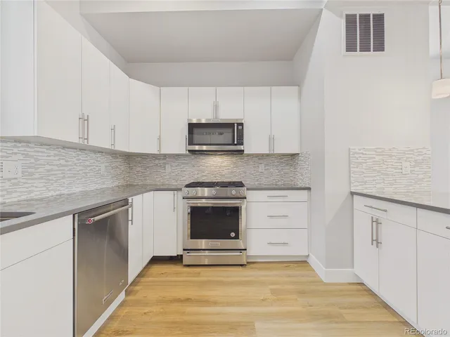 a kitchen with granite countertop white cabinets and stainless steel appliances