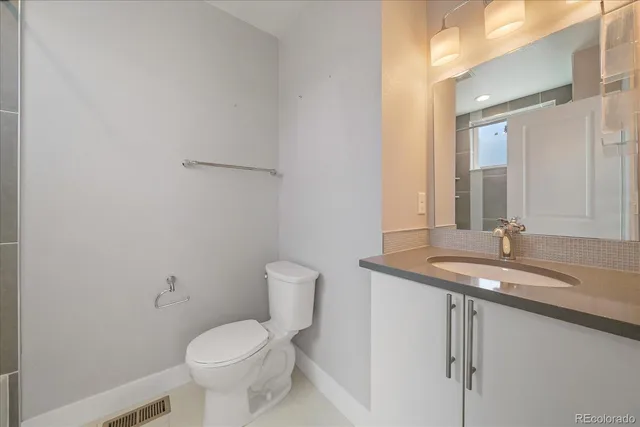 a bathroom with a granite countertop toilet sink and mirror