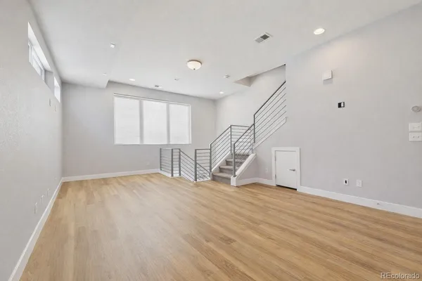 a view of an empty room with wooden floor and stairs