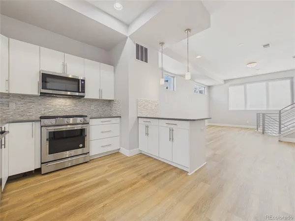 a kitchen with granite countertop a stove top oven a sink and a microwave area