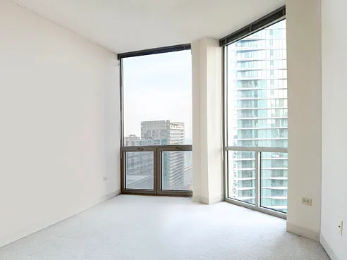 a view of an empty room with a window and a kitchen