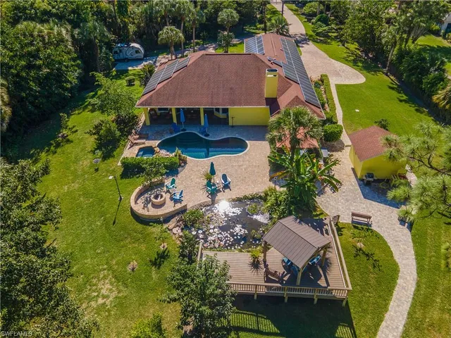an aerial view of a house with swimming pool a yard and mountain view in back