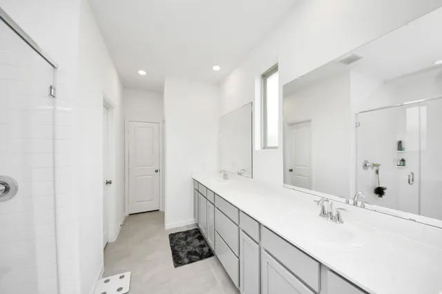 a spacious bathroom with a double vanity sink mirror and shower