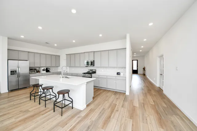 a kitchen with a sink a stove a refrigerator and white cabinets with wooden floor