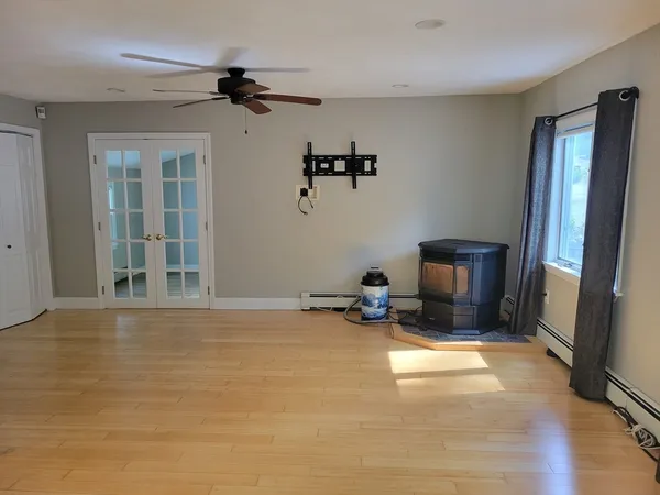 a view of a livingroom with a fireplace a ceiling fan and windows
