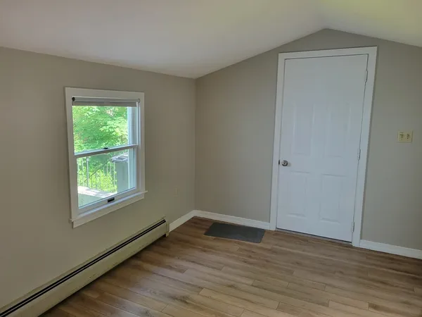a view of an empty room with wooden floor and a window