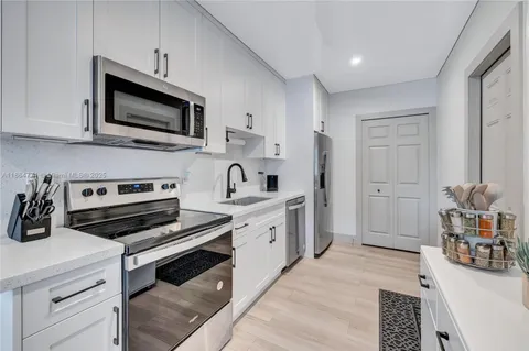 a kitchen with stainless steel appliances a white cabinets and a stove top oven