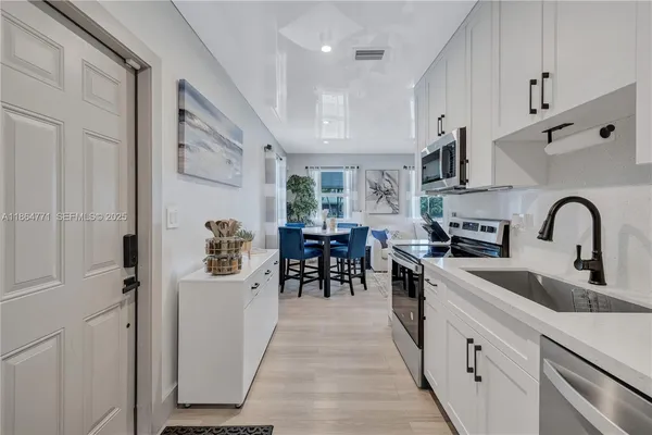 a kitchen with white cabinets and sink