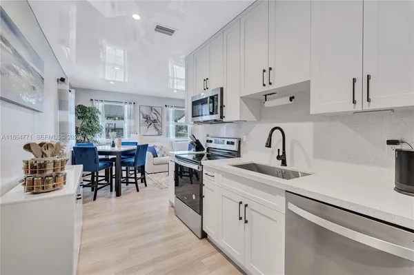 a kitchen with white cabinets and sink