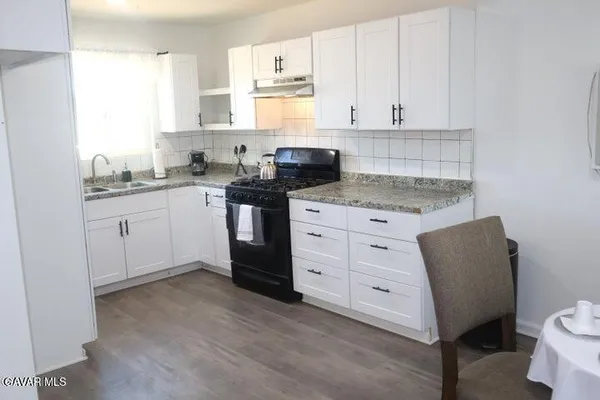 a kitchen with granite countertop white cabinets and white appliances