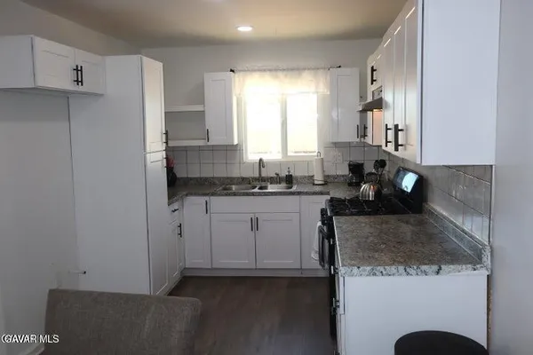 a kitchen with granite countertop a sink a stove and a refrigerator