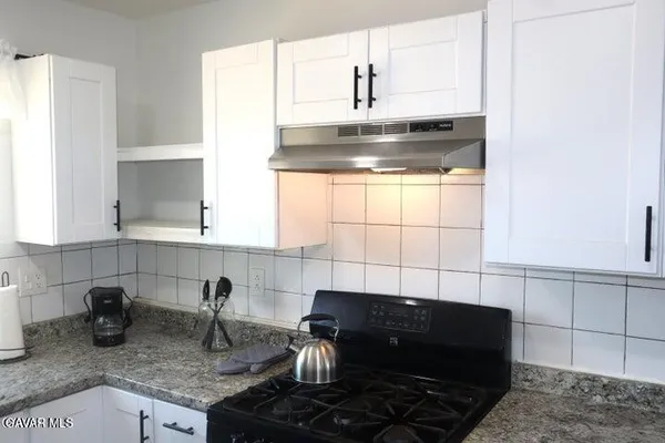 a kitchen with granite countertop a sink stove and cabinets