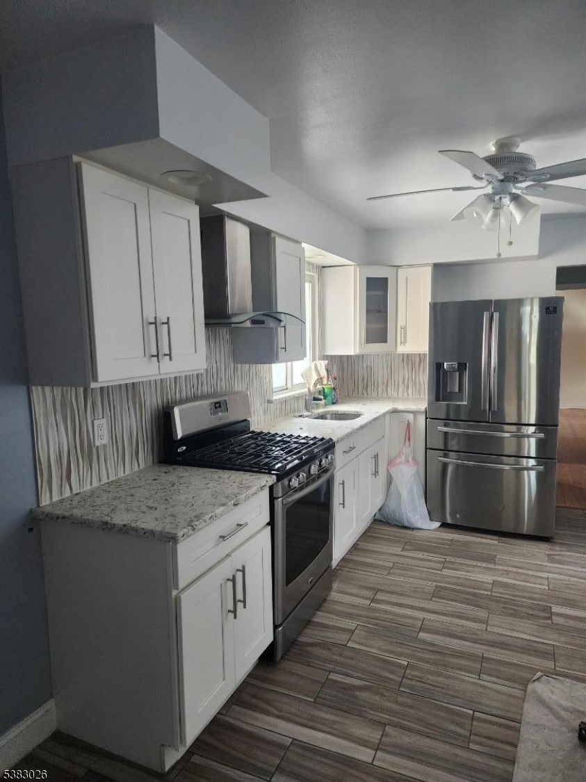 1371 Hamilton Street Elizabeth, NJ 07208 - Photo 5 of 9 a kitchen with stainless steel appliances granite countertop a stove a sink dishwasher a refrigerator and white cabinets with wooden floor