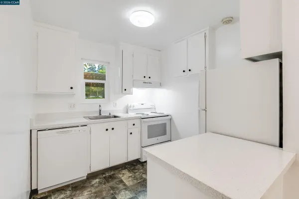 a kitchen with granite countertop white cabinets and white appliances