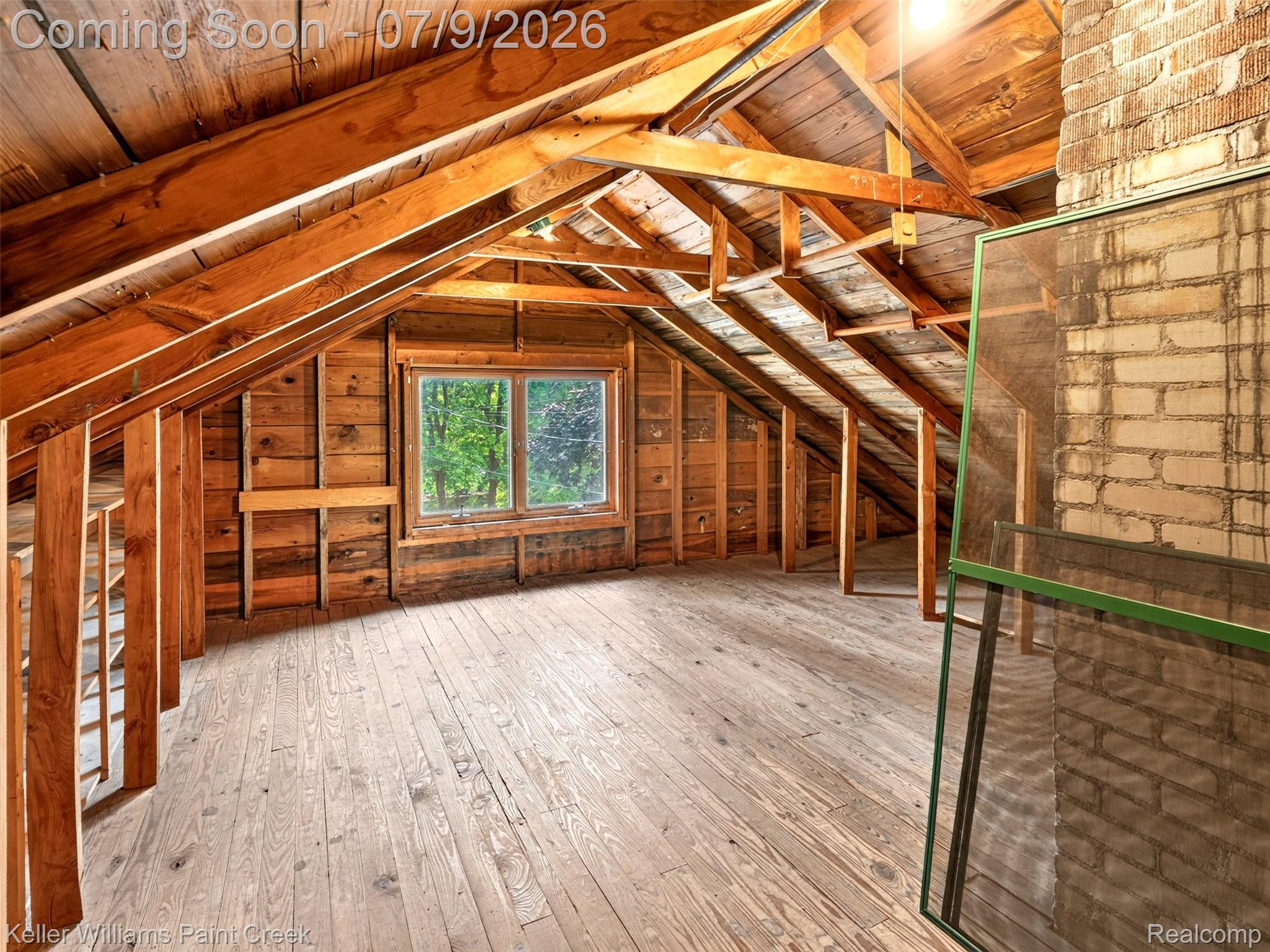204 Russell Road Kawkawlin, MI 48631 - Photo 42 of 82 Spacious unfinished attic featuring exposed wood beams, plank flooring, a double window, and a brick chimney