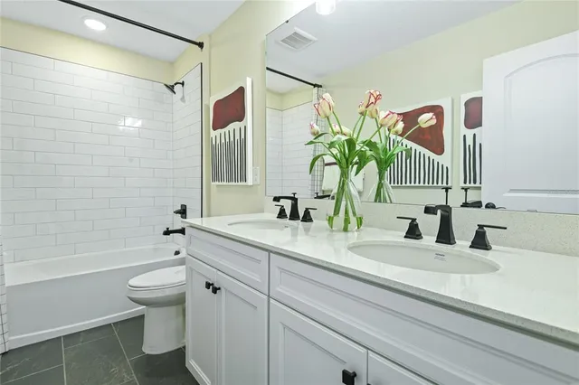 a bathroom with a granite countertop sink a toilet and shower
