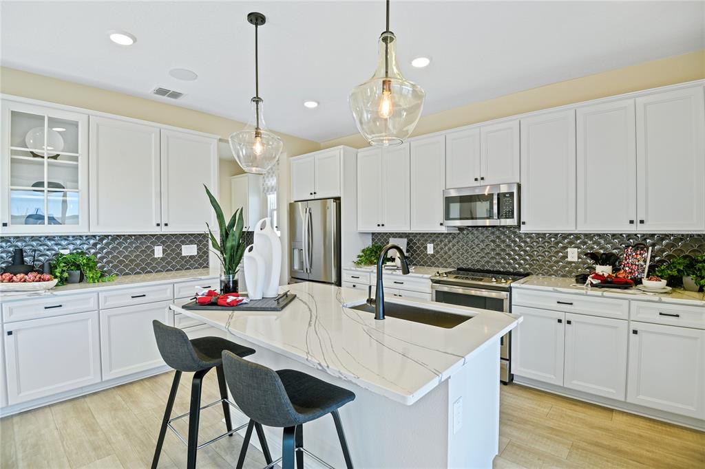3633 Sublett Loop Tavares, FL 32778 - Photo 5 of 31 a kitchen with white cabinets and chairs