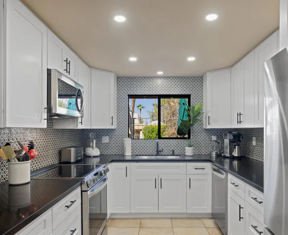 a kitchen with granite countertop white cabinets sink and stainless steel appliances