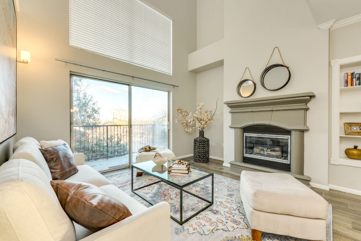 11203 Ranch Road 2222, Unit 901 Austin, TX 78730 - Photo 11 of 40 Living room featuring a glass covered fireplace, wood finished floors, a towering ceiling, and built in shelves