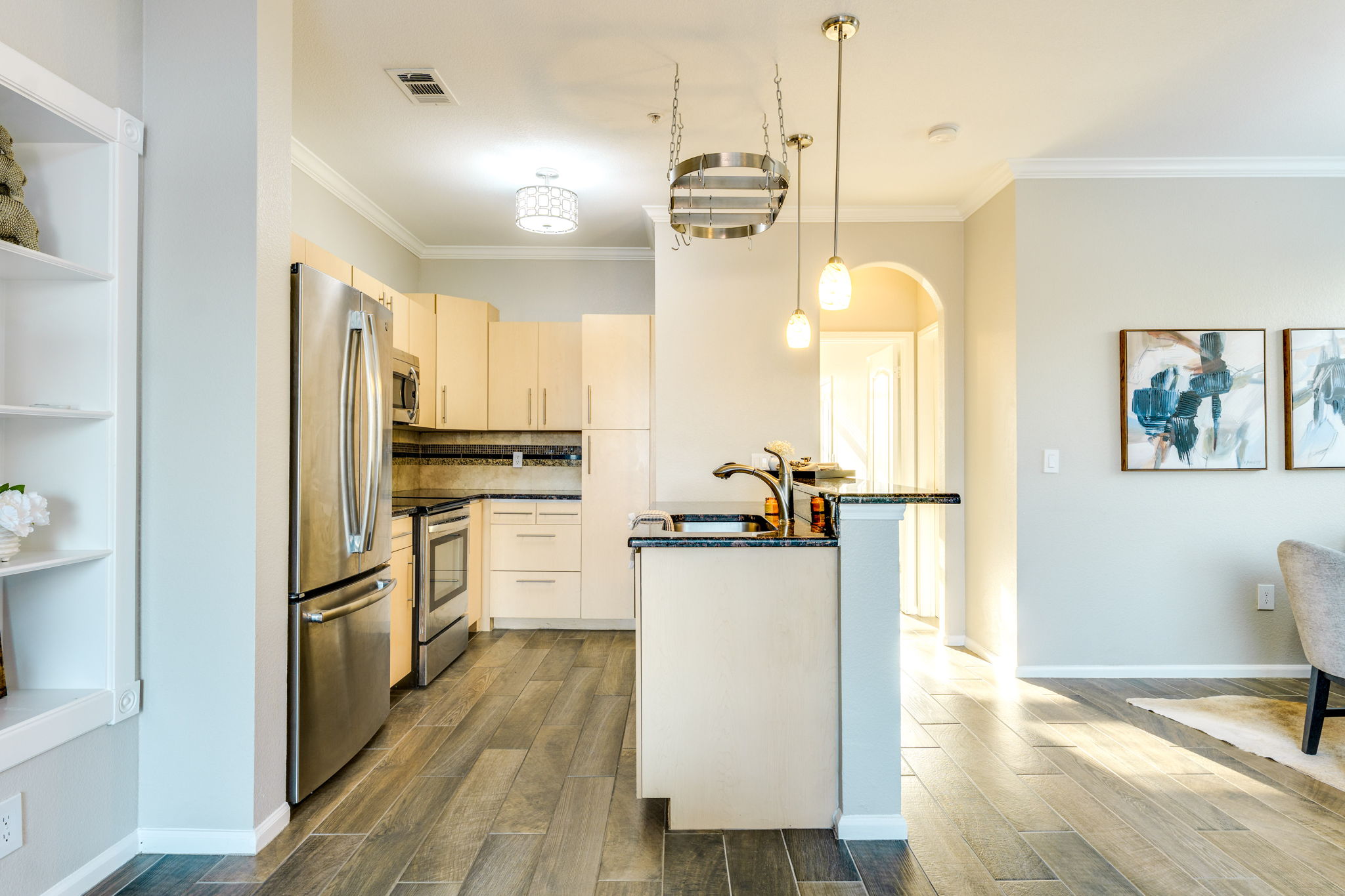 11203 Ranch Road 2222, Unit 901 Austin, TX 78732 - Photo 5 of 40 Kitchen featuring stainless steel appliances, wood tiled floors, ornamental molding, hanging light fixtures, and arched walkways