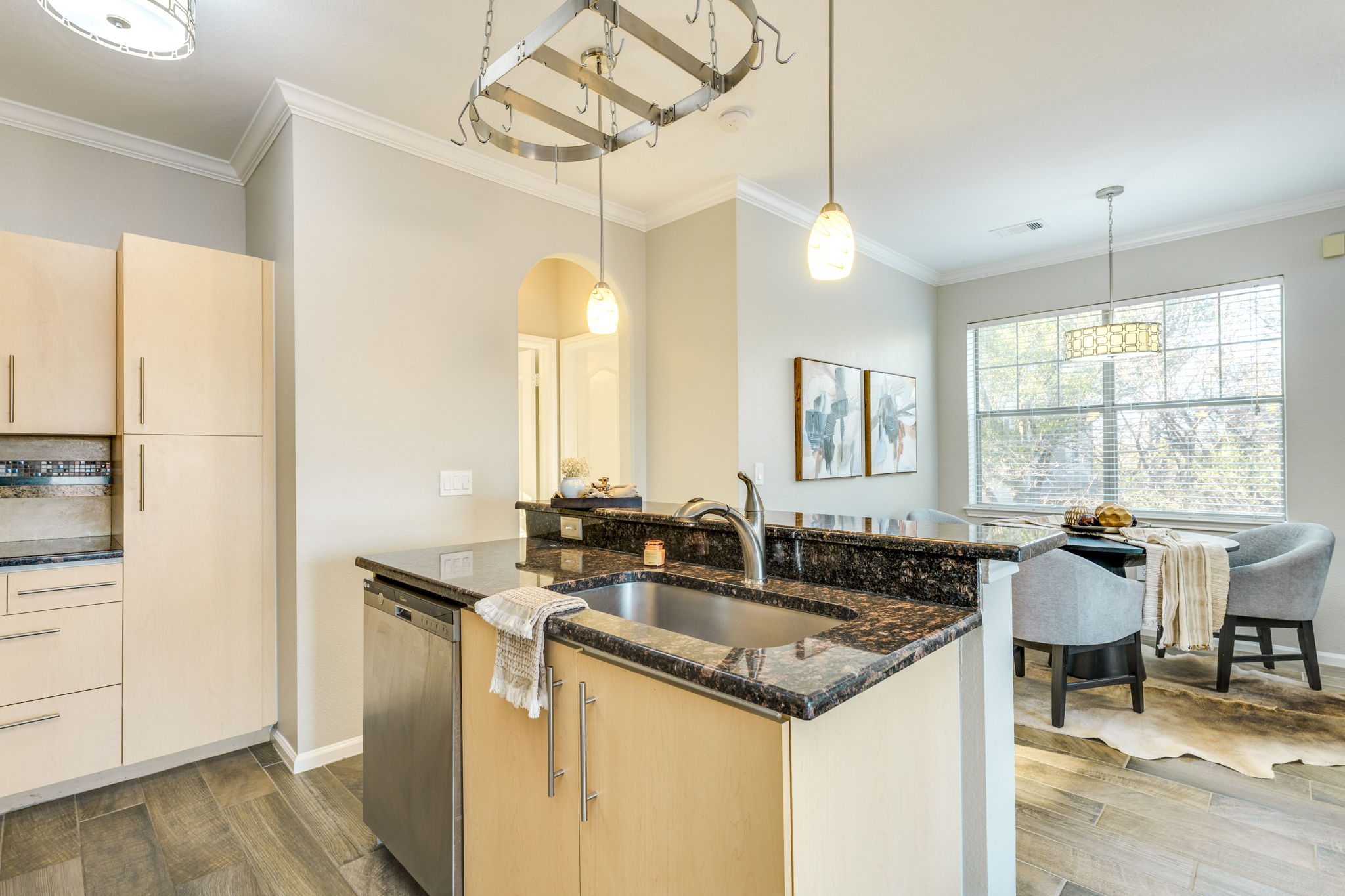 11203 Ranch Road 2222, Unit 901 Austin, TX 78732 - Photo 6 of 40 Kitchen featuring light brown cabinetry, dark stone counters, an island with sink, ornamental molding, and stainless steel dishwasher