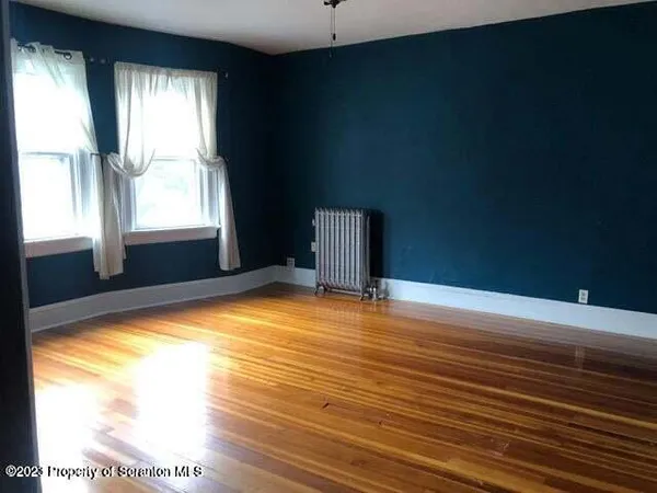 a view of empty room with window and wooden floor