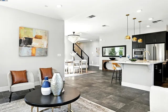 a living room with furniture kitchen view and a wooden floor